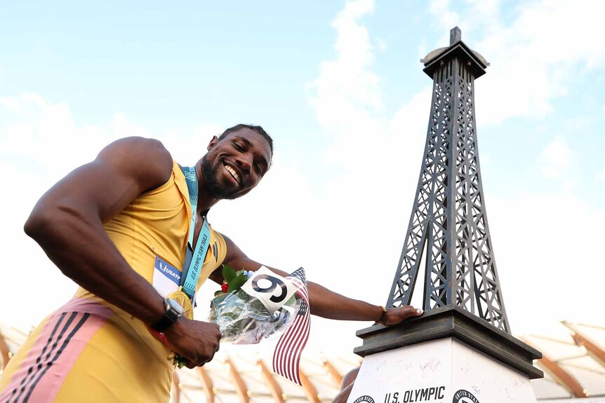 Noah Lyles poses with a miniature Eiffel Tower