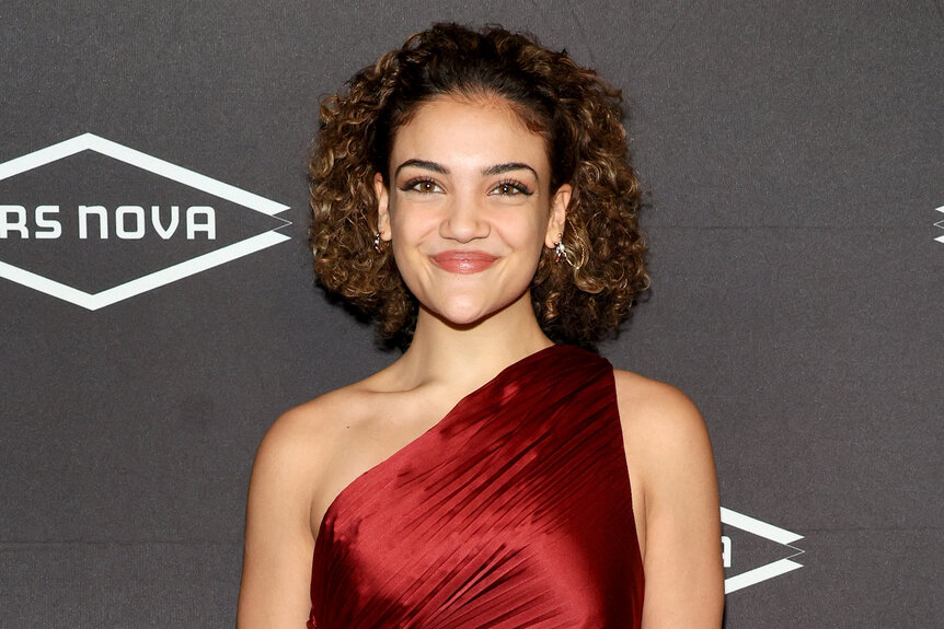 Laurie Hernandez smiles in a red dress on the red carpet