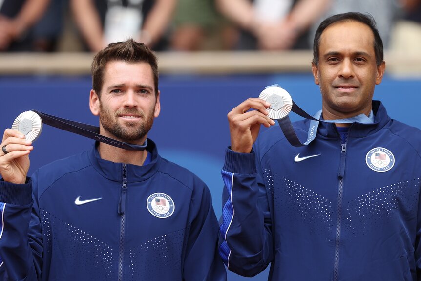 Austin Krajicek and Rajeev Ram hold up their silver medals in men's doubles tennis at the 2024 Olympics.