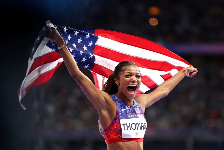 Gabrielle Thomas holding the American Flag after competing in the Paris 2024 Olympics.