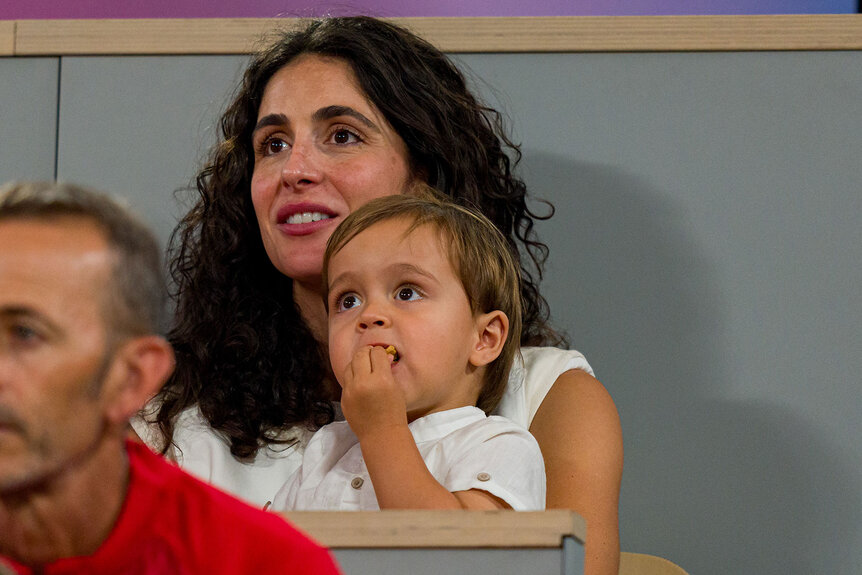 Maria Francisca Perello holds son Rafael Nadal Junior as they watch Rafael Nadal and partner Carlos Alcaraz of Spain compete against Andres Molteni and Maximo Gonzalez of Argentina