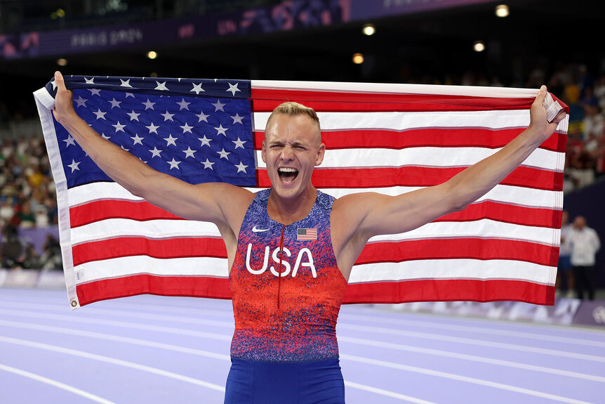 Sam Kendricks yelling while holding the American flag after winning Silver at the Paris 2024 Olympics.