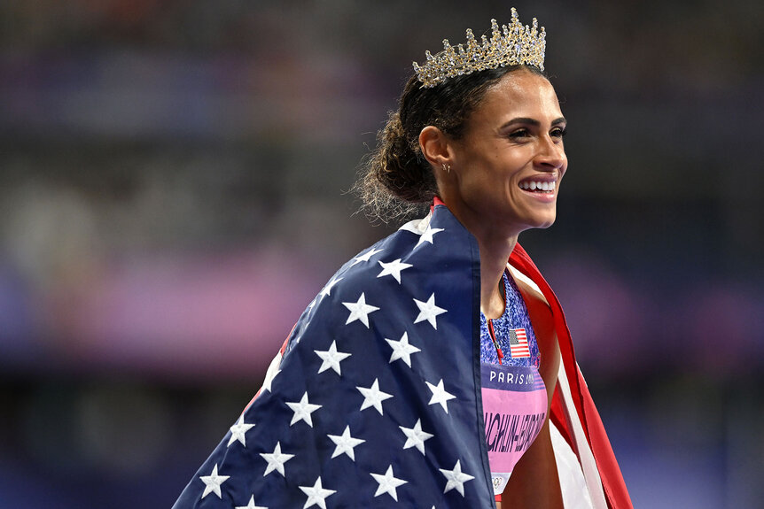 Sydney Mclaughlin-Levrone smiling with the American flag and a crown at Paris 2024 Olympics.