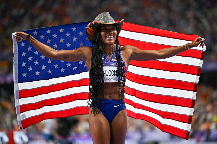 Tara Davis-Woodhall smiling with an American flag and cowboy hat at the Paris 2024 Olympics.