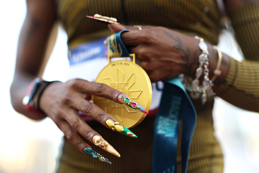 Sha'carri Richardson holds a gold medal showing off her nails