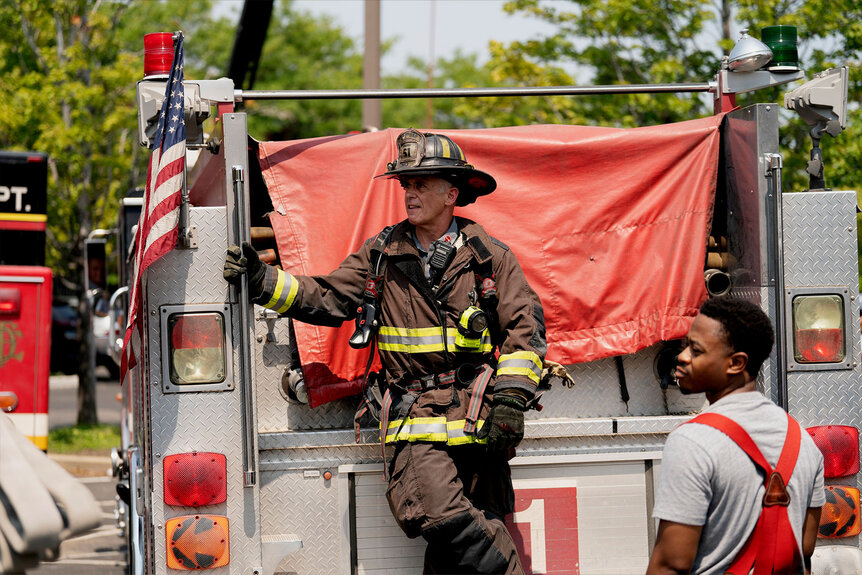 Christopher Herrmann stands on the ledge of the fire truck