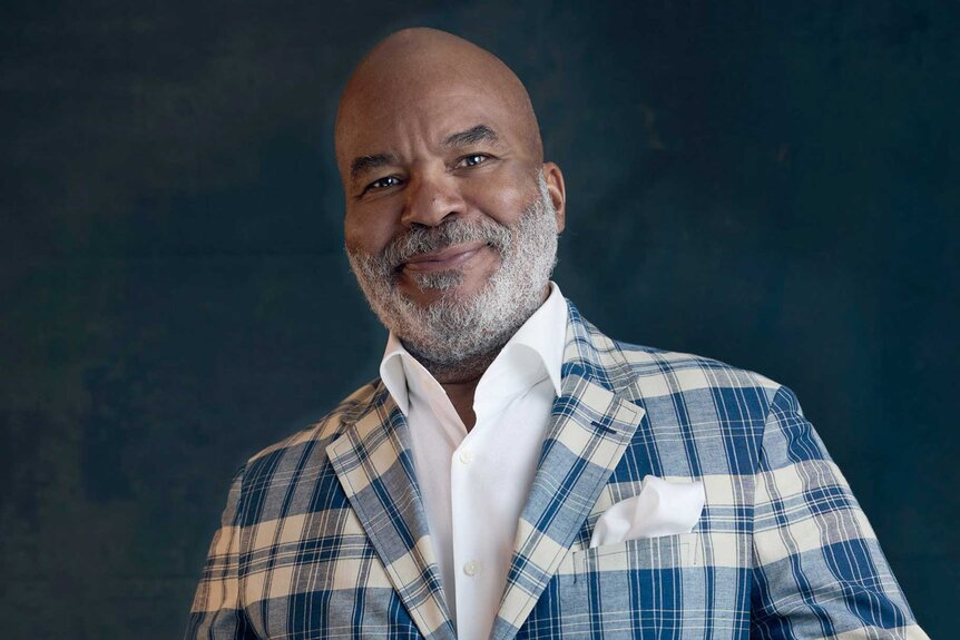 David Alan Grier smiles in a blue plaid suit