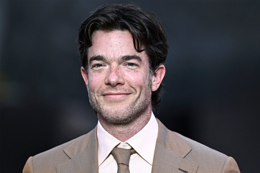 John Mulaney smiles in a tan suite in Paris