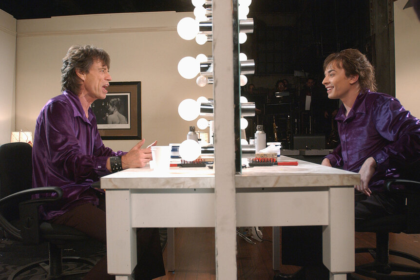 Mick Jagger sits as himself and Jimmy Fallon as Mick Jaggers reflection in an SNL skit