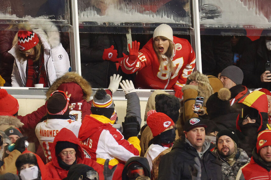 Taylor Swift high fives fans during the AFC Wild Card Playoffs between the Miami Dolphins and the Kansas City Chiefs