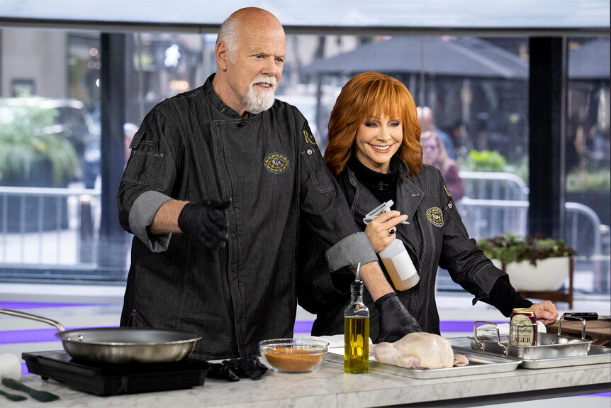 Rex Linn and Reba McEntire stand behind a cooking counter while wearing chef's jackets on the TODAY show