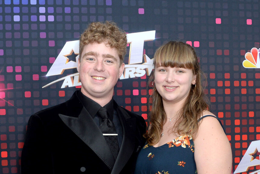 Tom Ball and Hannah Ball posing together in front of a step and repeat.