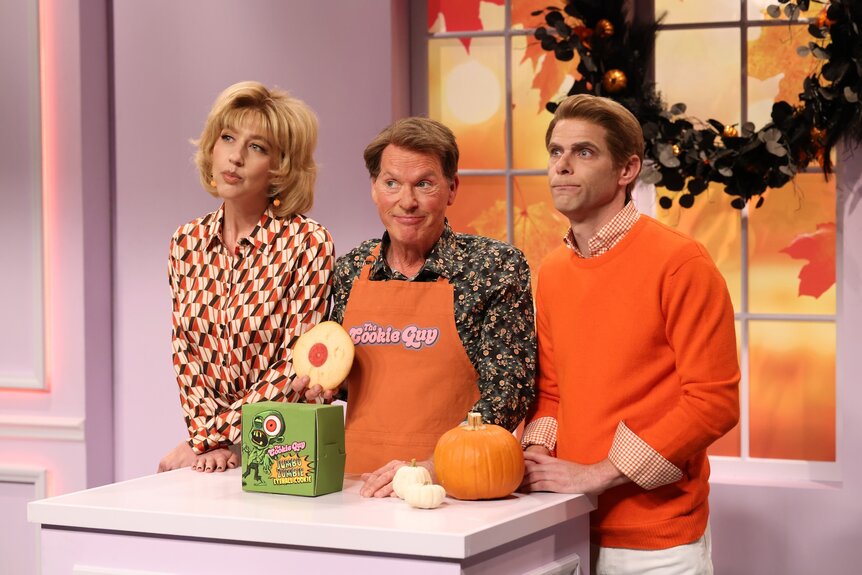 Heidi Gardner Michael Keaton and Mikey Day standing behind a table