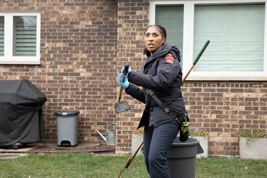 Gianna Mackey (Adriyan Rae) holds a hoe on a front lawn on Chicago Fire Season 9 Episode 3.