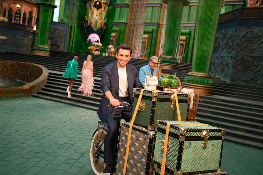 Jonathan Bailey rides a bike with luggage on Defying Gravity The Curtain Rises On Wicked