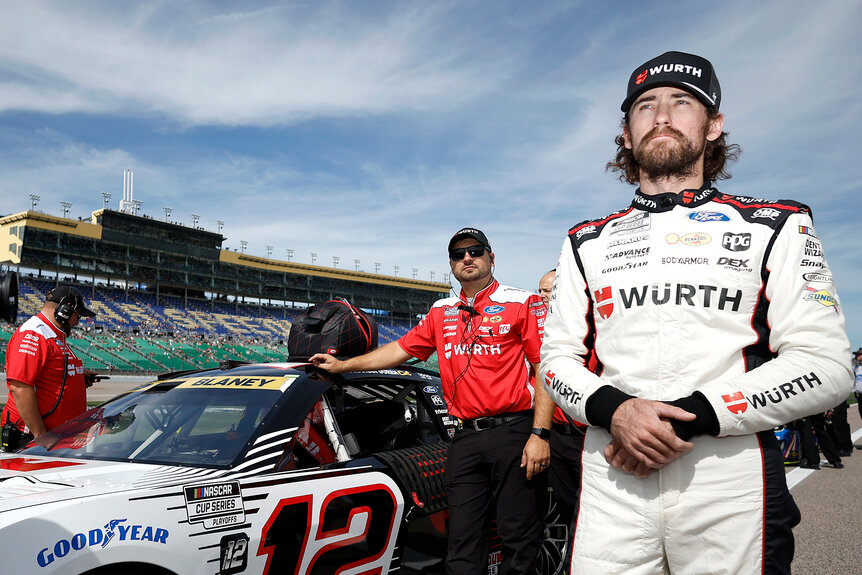 NASCAR driver Ryan Blaney stands in front of his car on the race track