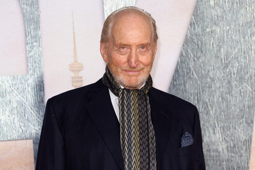 Charles Dance wears a scarg and black jacket on the red carpet