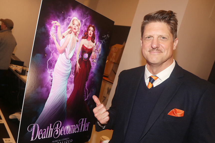 Christopher Sieber points at a poster for death becomes her