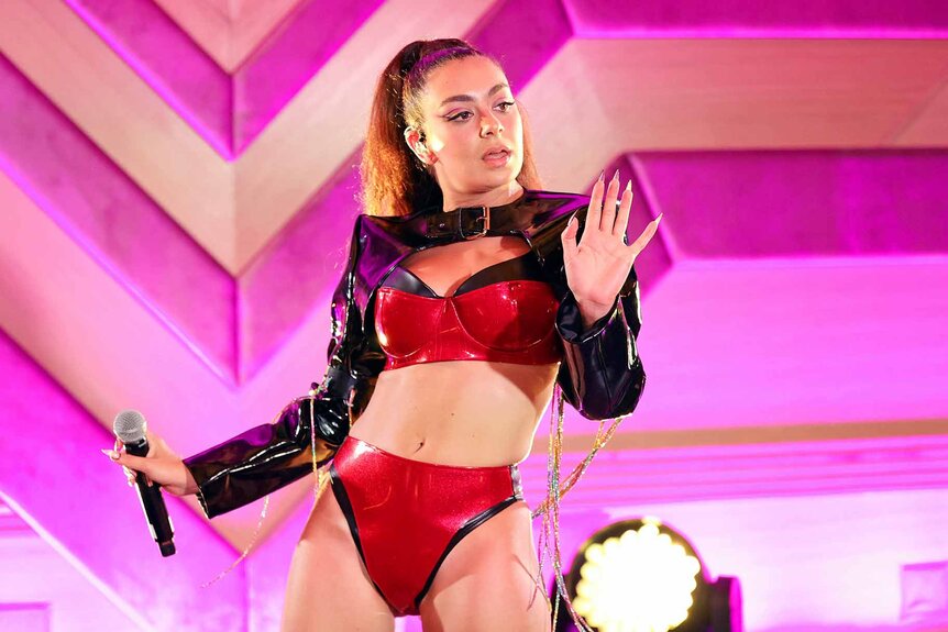 Charli XCX performs in a red outfit onstage.