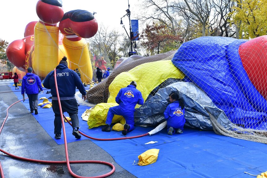 Workers dressed in blue inflate balloons for the Macy's Thanksgiving Day Parade.