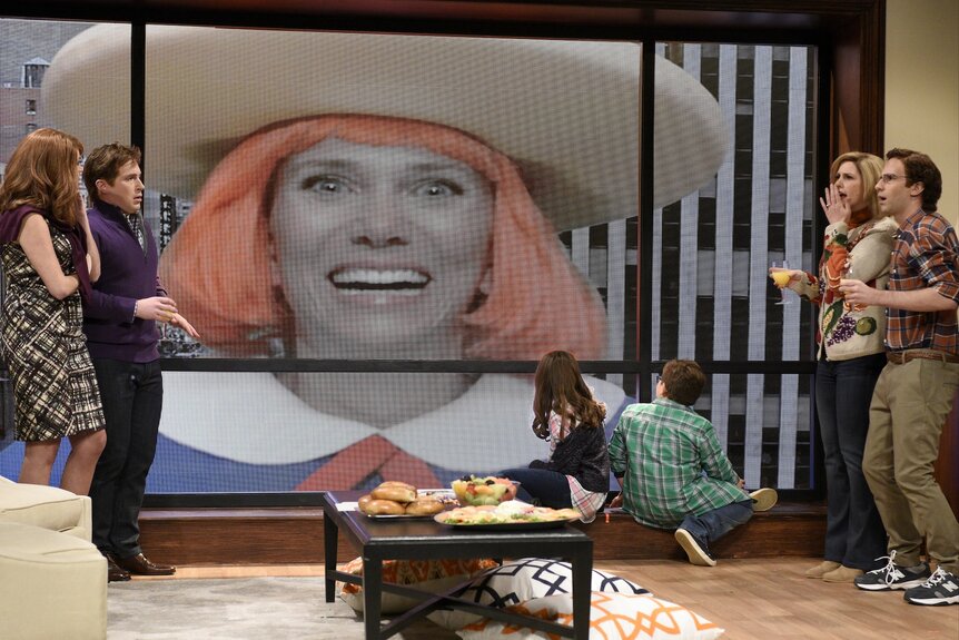 The cast of Saturday Night Live watches Kristen Wiig on a screen on Episode 1711.