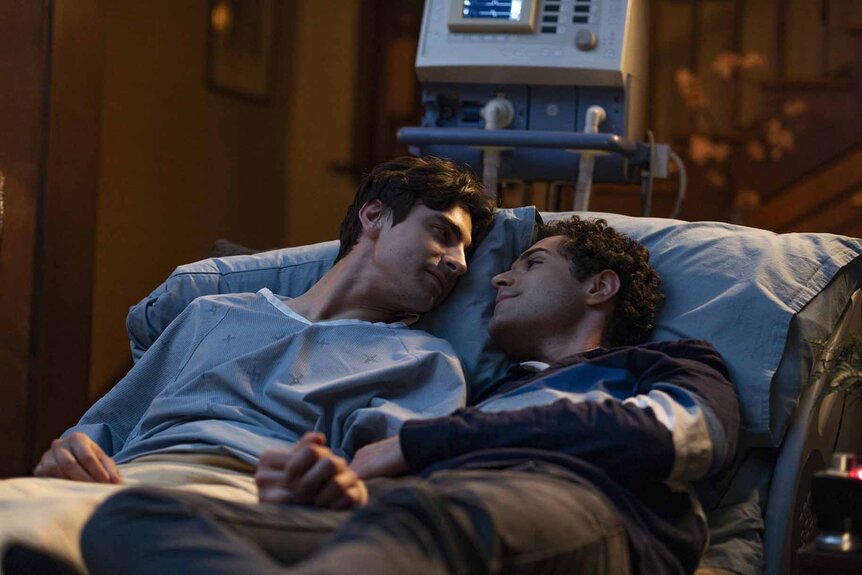 Roman (John Doe) (Alex Ozerov-Meyer) and Alex (Mishka Yarovoy) cuddle in a hospital bed in Brilliant Minds Episode 107.