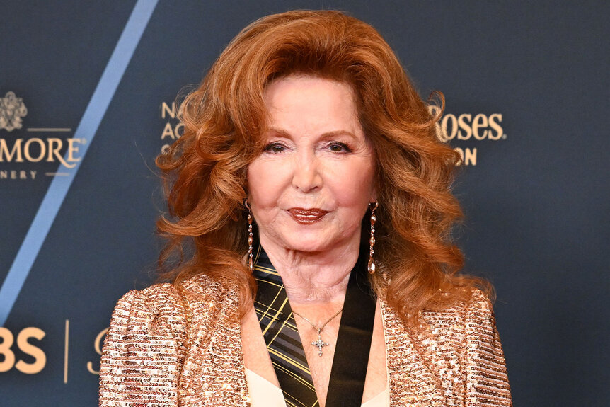 Suzanne Rogers posing in front of a step and repeat.