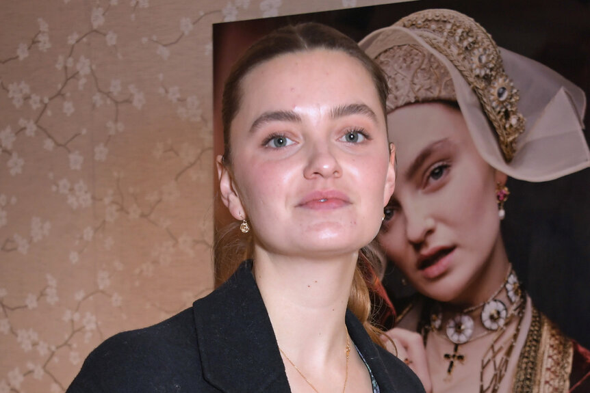 Rosanna Adams poses in front of a painting of a woman.