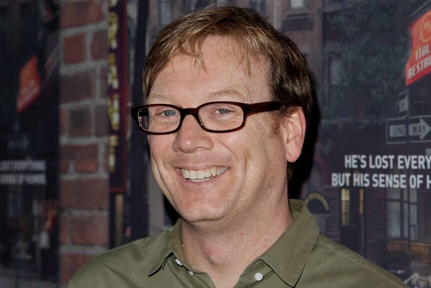 Andy Daly smiles in glasses and a green shirt.