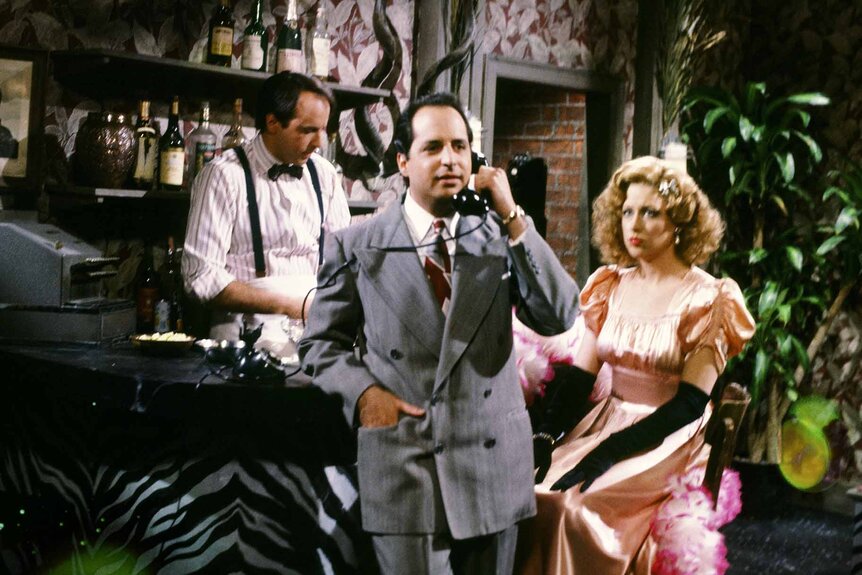 Eddie Spimozo (Jon Lovitz) speaks on the phone at a bar as Nancy Maloney (Victoria Jackson) watches during an SNL sketch.