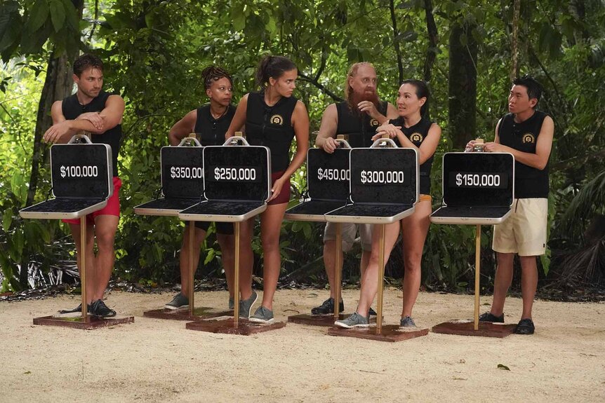 The cast stands with open briefcases on Deal or No Deal Island Episode 201.