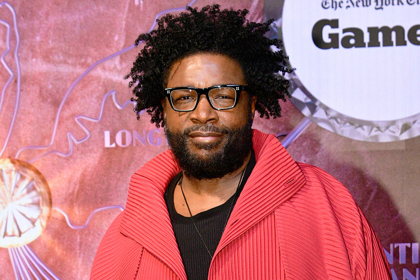 Questlove stands on the red carpet in a red jacket