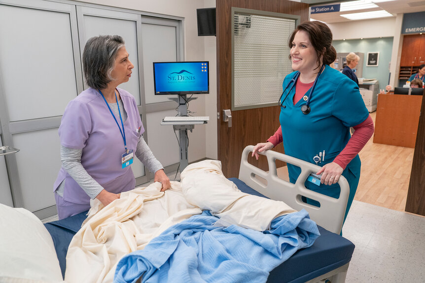 Alex and Debbie stand in front of a hospital bed on St. Denis Medical Season 1 Episode 5