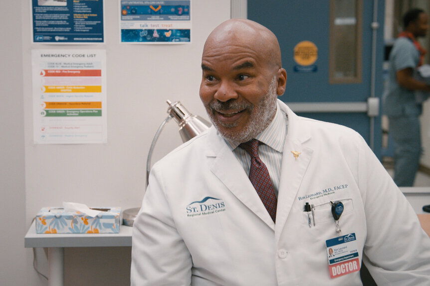 Dr Ron smiles in his dr. coat on st denis mecial season 1 episode 6