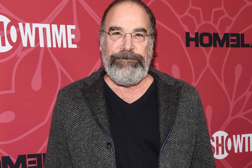 Mandy Patinkin wears a grey blazer with a black shirt.