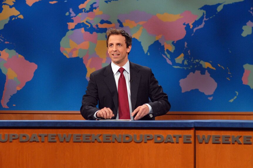 Seth Meyers sits in front of a colorful map of the world on SNL Episode 1537.