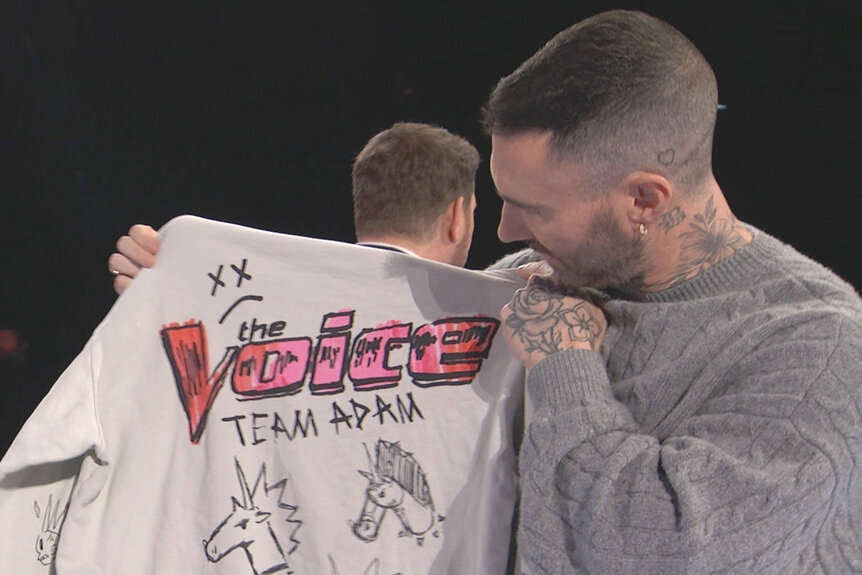 Adam Levine holds up a sweatshirt for his team on The Voice Season 27 Episode 1